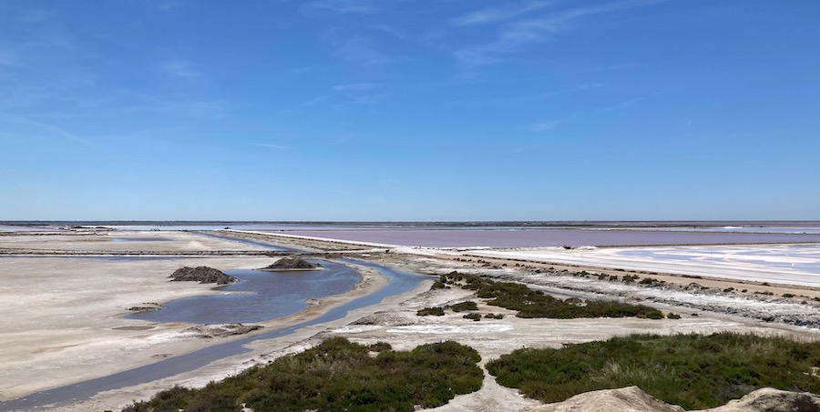Das Verdunstungsbecken (rötlich) und dahinter das Meer.