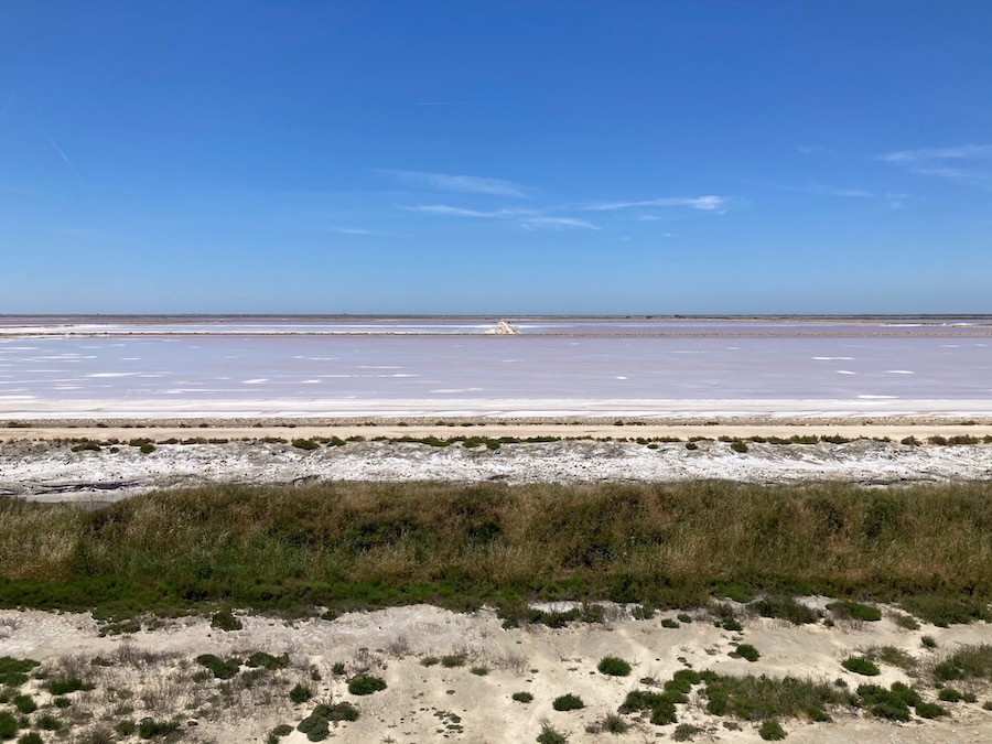 Das Verdunstungsbecken (rötlich) und dahinter das Meer.
